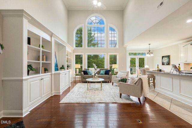 a kitchen with stainless steel appliances granite countertop a refrigerator a sink a dining table and chairs with wooden floor