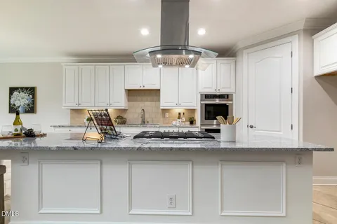 a kitchen with stainless steel appliances granite countertop a refrigerator a sink a dining table and chairs with wooden floor