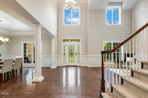 a dining room with wooden floor a chandelier a glass table and chairs