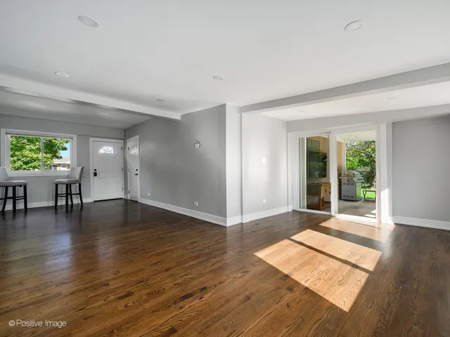 a view of an empty room with window and wooden floor