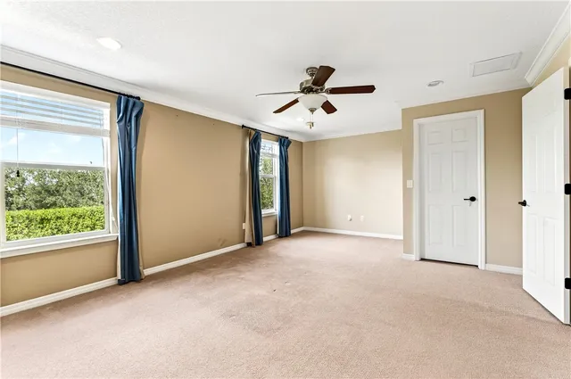 a view of a big room with windows and chandelier fan