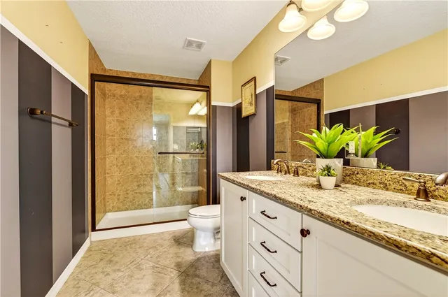 a bathroom with a granite countertop sink a toilet and shower