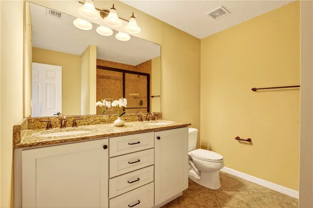 a bathroom with a granite countertop sink mirror vanity and toilet