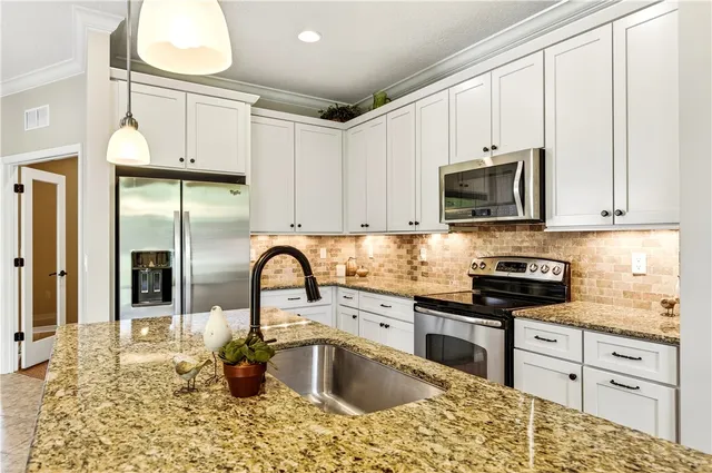 a kitchen with stainless steel appliances kitchen island granite countertop a sink a stove and cabinets