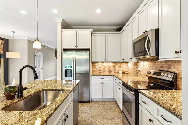 a kitchen with granite countertop a sink stainless steel appliances and cabinets
