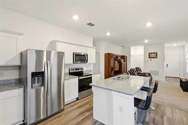 a kitchen with stainless steel appliances granite countertop a refrigerator stove microwave and sink