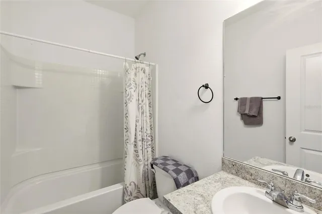 a bathroom with a granite countertop bathtub sink vanity mirror and toilet