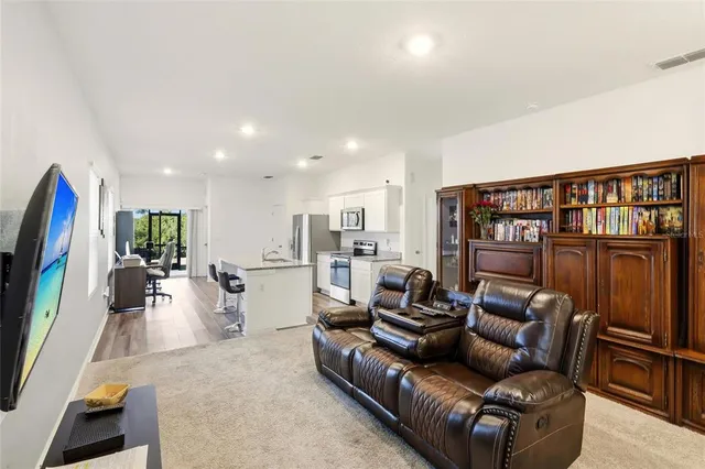 a living room with furniture a flat screen tv and a floor to ceiling window