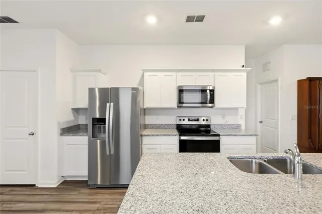 a kitchen with granite countertop a refrigerator and a sink