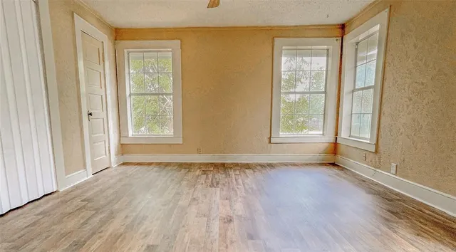 a view of an empty room with wooden floor and a window