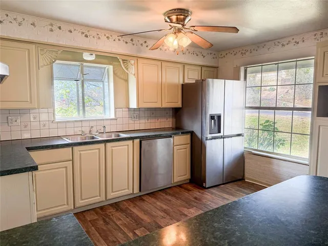 an empty room with wooden floor fireplace and windows