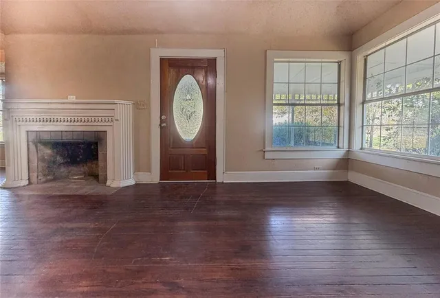 an empty room with wooden floor a fireplace and windows