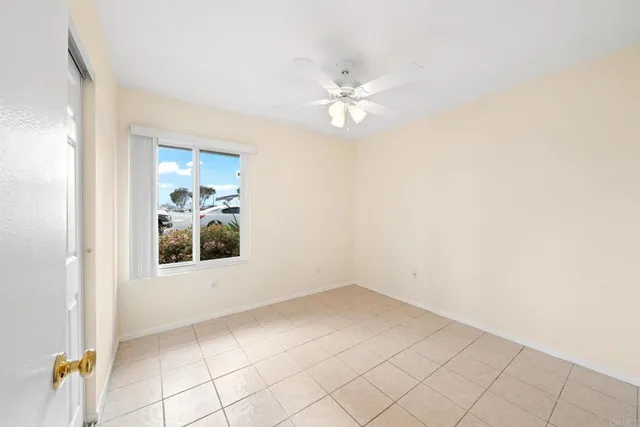 an empty room with chandelier fan and windows