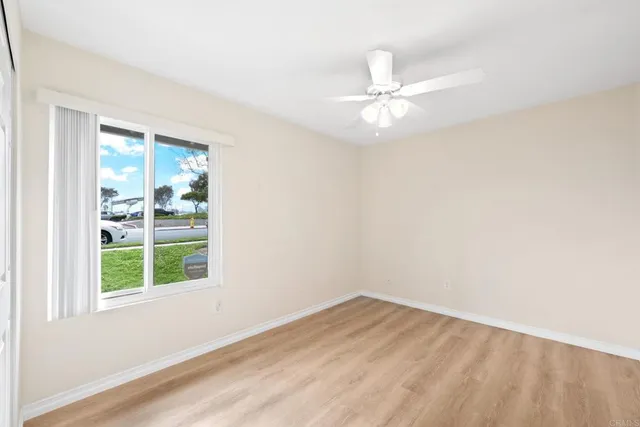 an empty room with a window and ceiling fan
