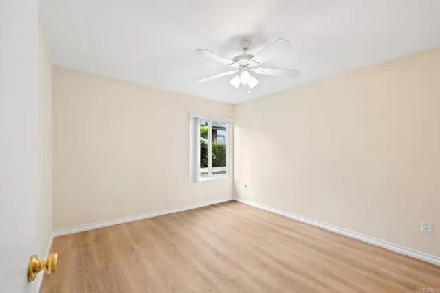 an empty room with wooden floor fan and windows
