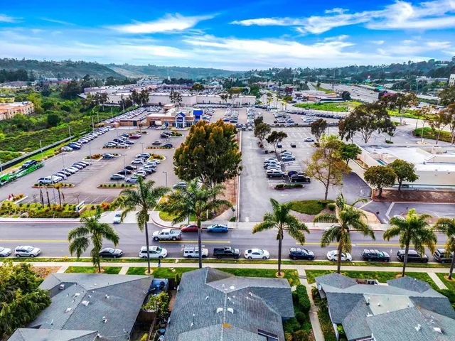 an aerial view of a city with lots of residential buildings ocean and mountain view in back