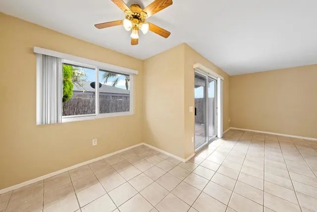 a view of an empty room with window and chandelier fan