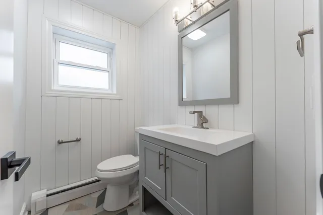 a bathroom with a toilet a sink a mirror and a window