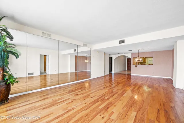 a view of empty room with wooden floor and plants
