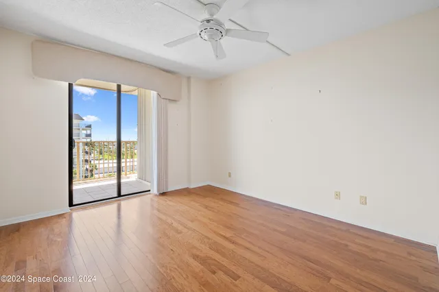 an empty room with wooden floor and ceiling fan