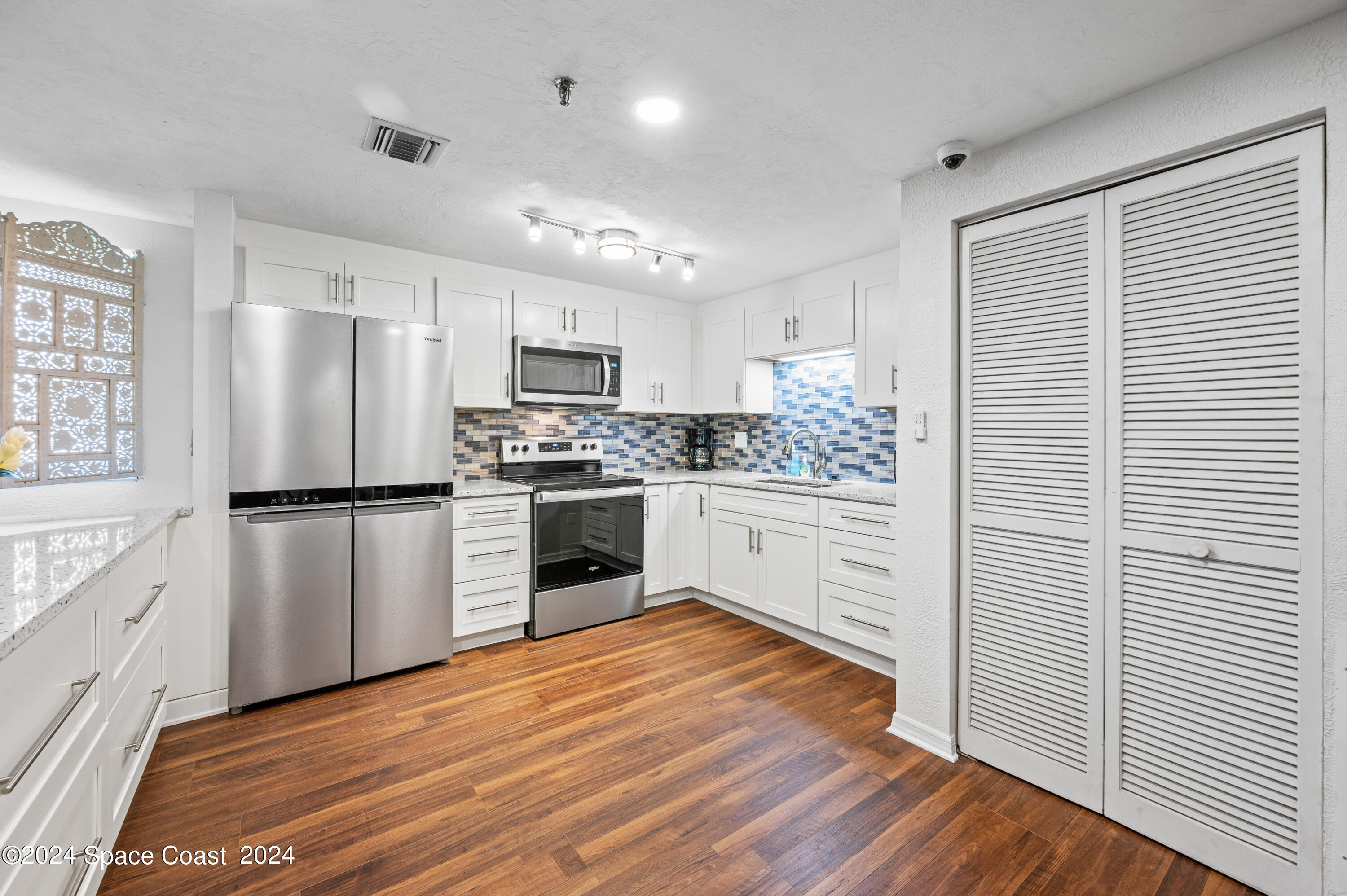 750 North Atlantic Avenue, Unit 608 Cocoa Beach, FL 32931 - Photo 32 of 39 a kitchen with white cabinets stainless steel appliances and wooden floor