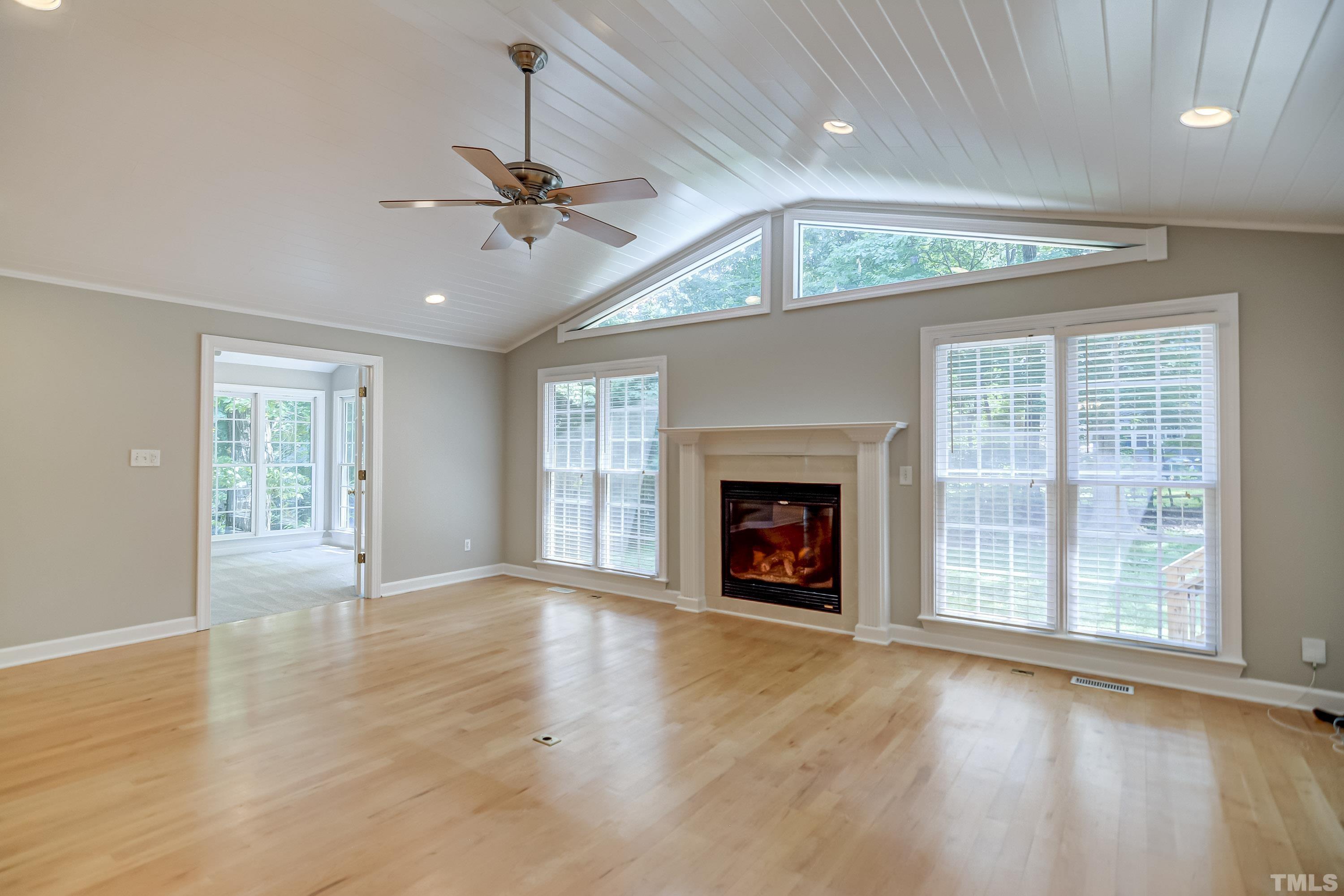 8313 Seagate Drive Raleigh, NC 27615 - Photo 8 of 24 an empty room with windows fireplace and a ceiling fan