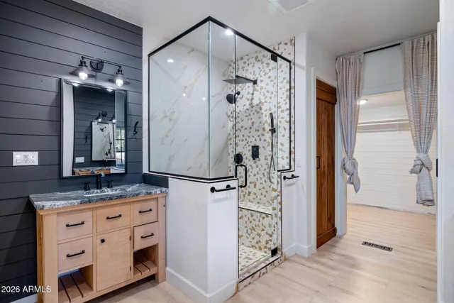 a bathroom with a granite countertop sink a mirror and shower