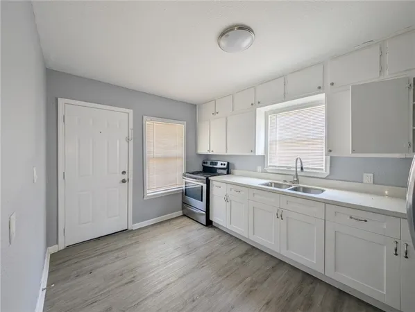 a large white kitchen with a sink and dishwasher a stove with wooden floor