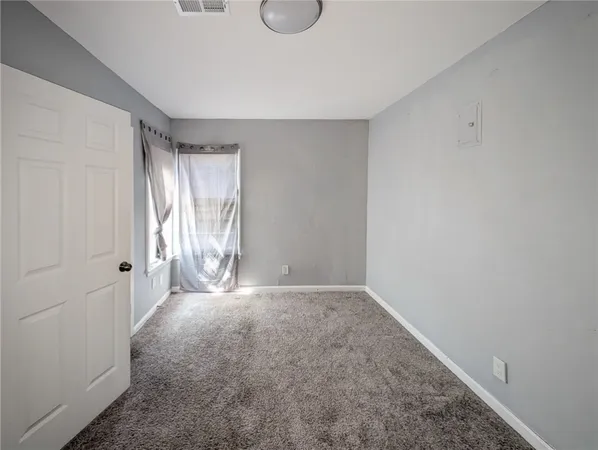 a view of an empty room with window and closet area