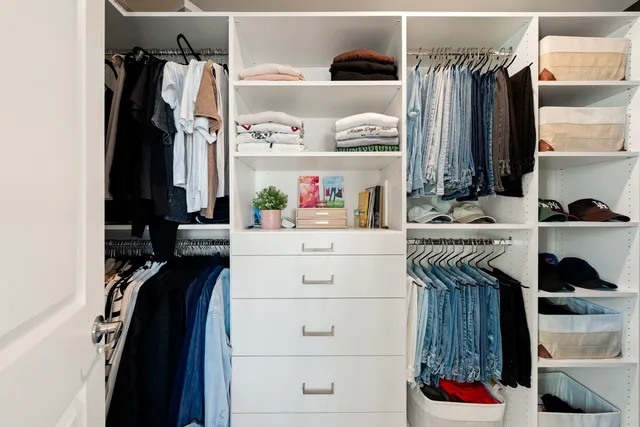 a view of walk in closet with clothes and shoes