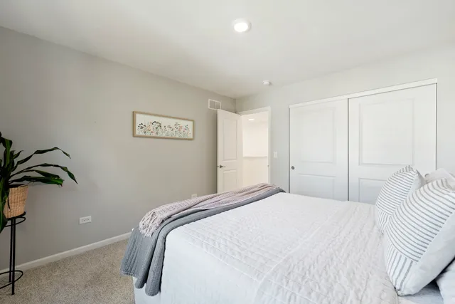 a bedroom with a bed and a potted plant on the dresser