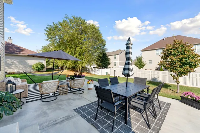 a view of a patio with a table and chairs under an umbrella with potted plants