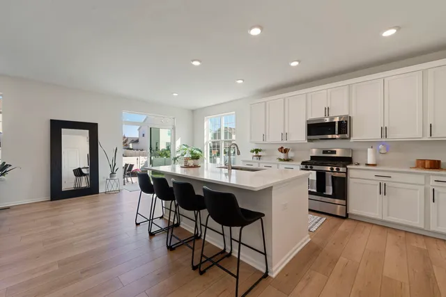 a kitchen with stainless steel appliances granite countertop a table chairs sink and cabinets