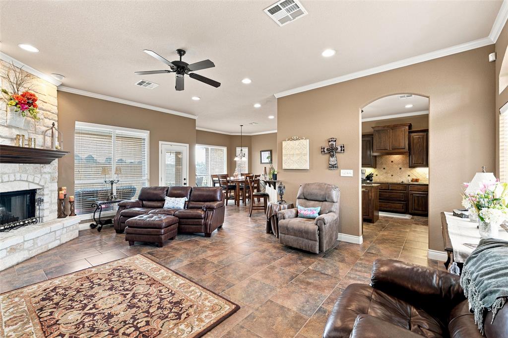 845 County Line Road West West, TX 76691 - Photo 4 of 36 Spacious open-concept living area featuring stone fireplace, ceiling fan, crown molding, and large windows with blinds