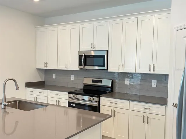 a kitchen with granite countertop white cabinets and stainless steel appliances