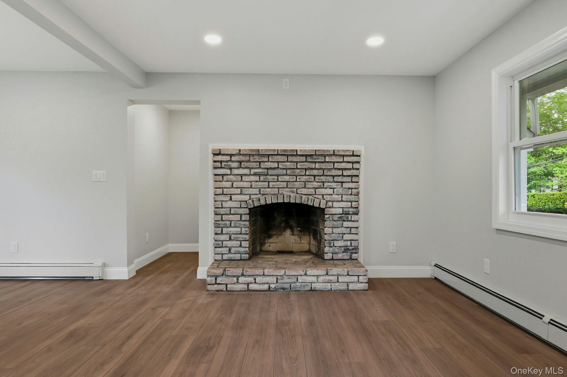 101 Rustic Road Centereach, NY 11720 - Photo 14 of 42 an empty room with wooden floor a fireplace and windows