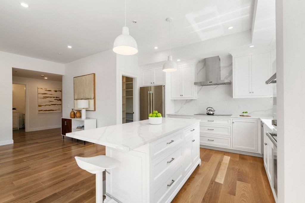 400 Hunnewell Street, Unit 103 Needham, MA 02494 - Photo 11 of 20 a large white kitchen with lots of counter space wooden floor and stainless steel appliances