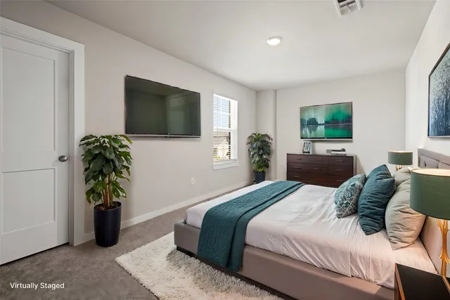 a bedroom with a bed table and a flat screen tv