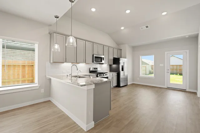 a kitchen with stainless steel appliances granite countertop a refrigerator a sink dishwasher a stove and white countertops with wooden floor