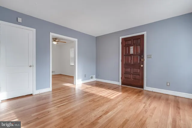 a view of an empty room with wooden floor and closet