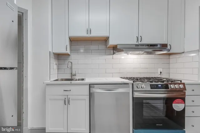 a kitchen with stainless steel appliances granite countertop white cabinets and a stove