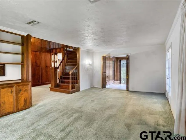a view of an empty room with window and a kitchen