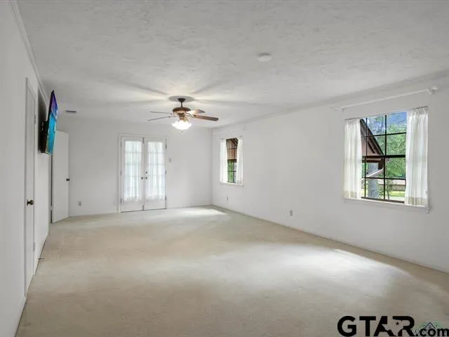 an empty room with windows and chandelier fan