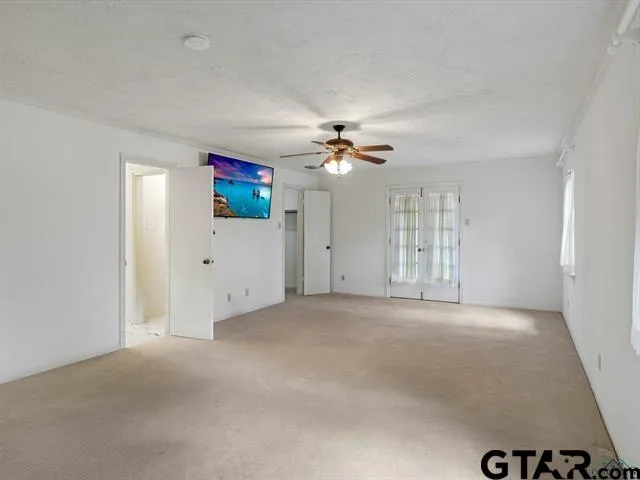 an empty room with chandelier fan and windows
