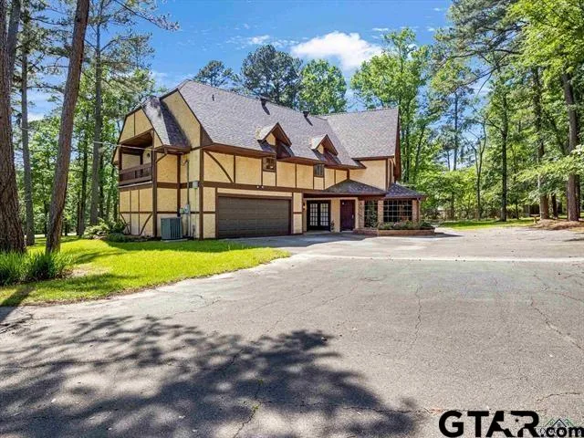 a view of a house with a small yard and large trees