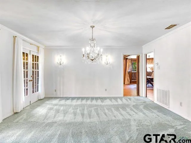 a view of a livingroom with a chandelier fan and windows