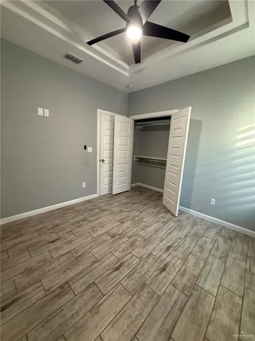 a view of empty room with wooden floor and ceiling fan