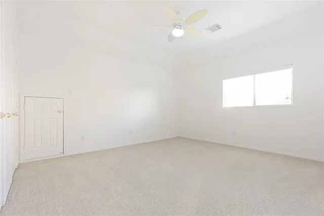an empty room with a window and a ceiling fan