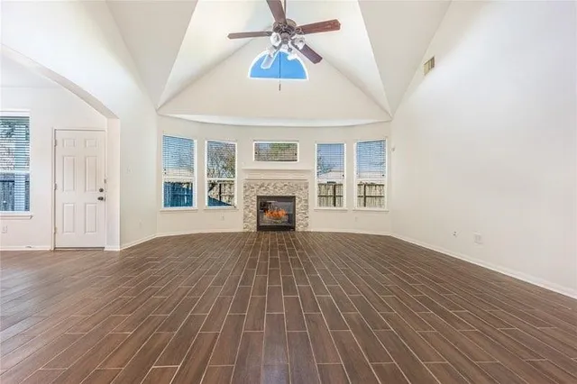 an empty room with wooden floor fireplace and a window