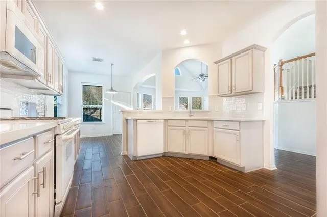a kitchen with granite countertop white cabinets and wooden floor
